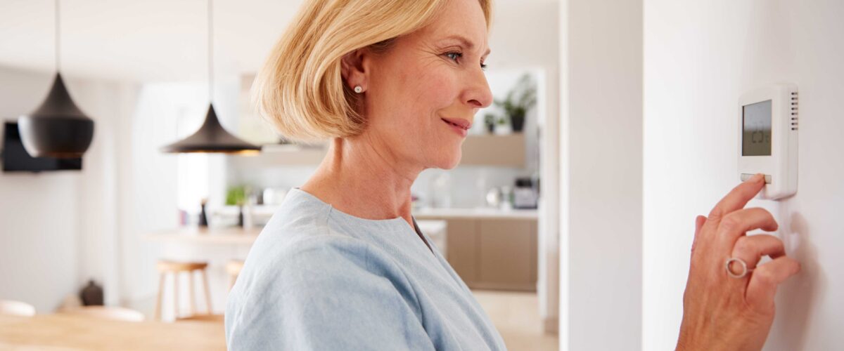 How to check the boiler - Lady changing her heating thermostat on the wall of her home